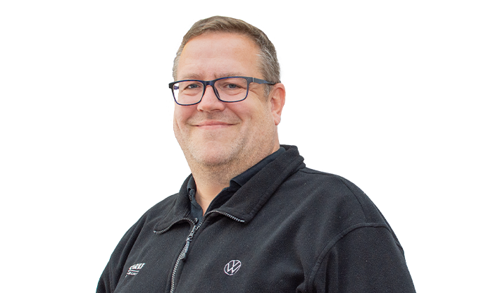 Portrait eines Mitarbeiters mit Brille, schwarzen Hemd und kurzen Haaren. 